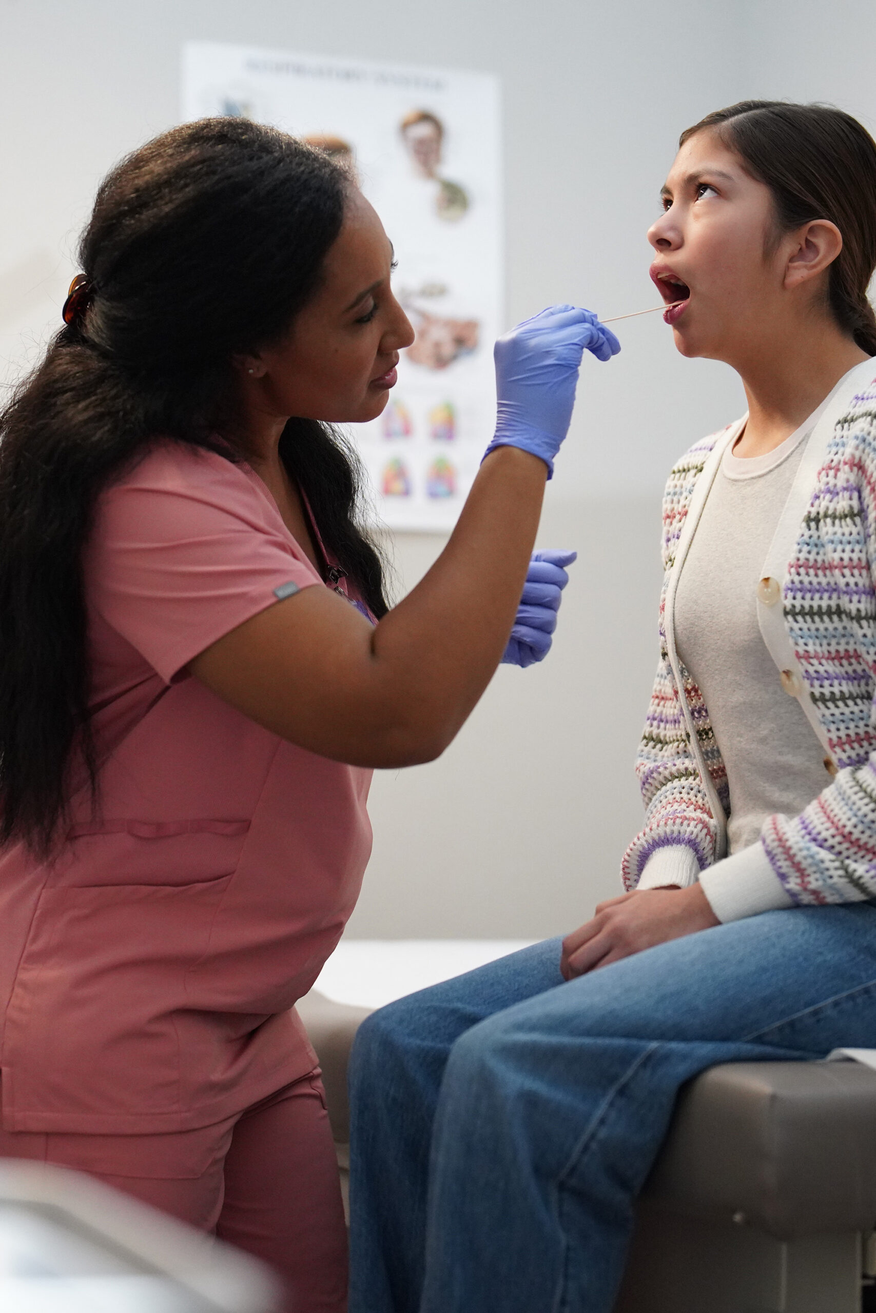 Nurse examining mouth of a young woman patient with a tongue depressor