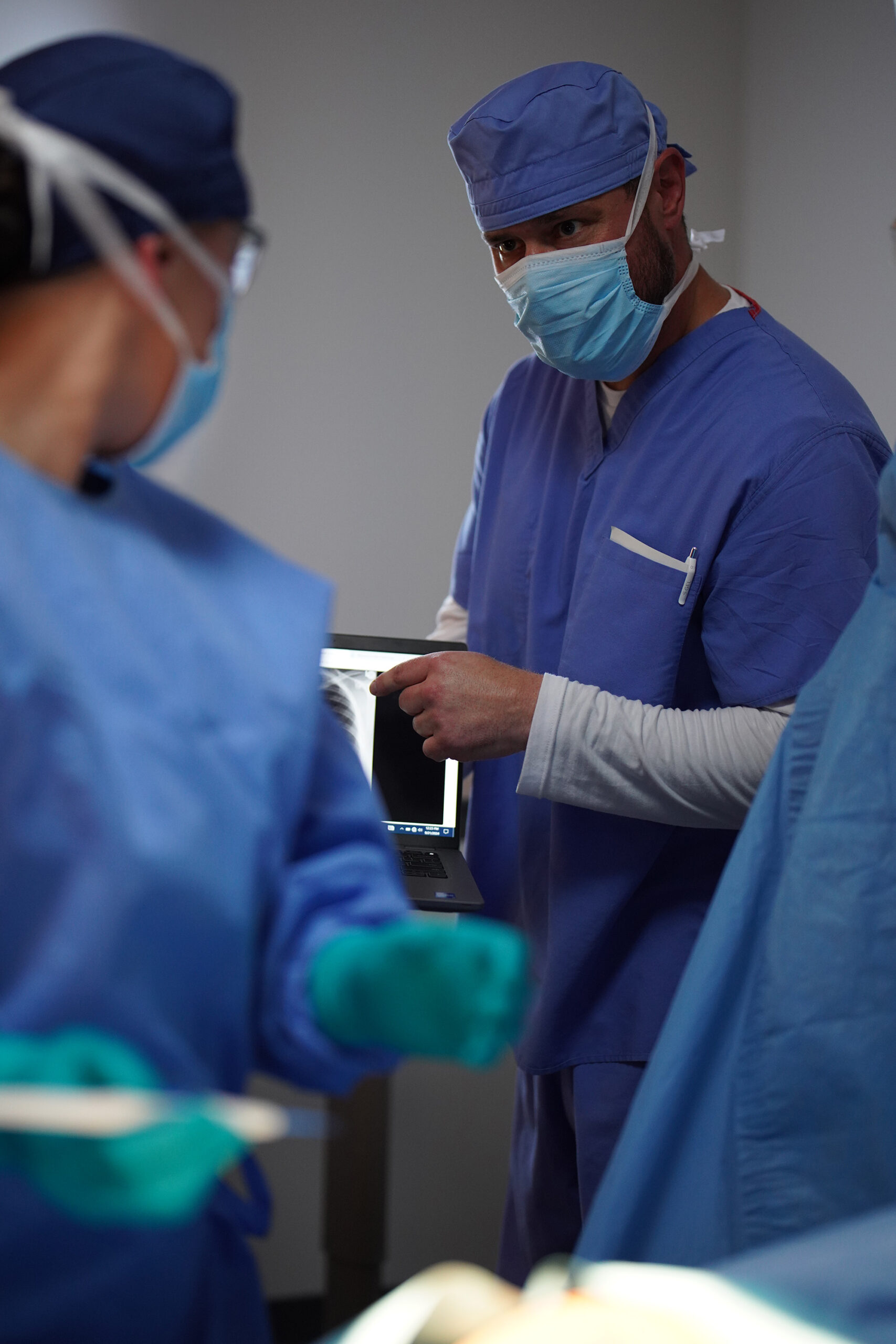 Nurse in the operating room using a laptop to point out information to the surgeon
